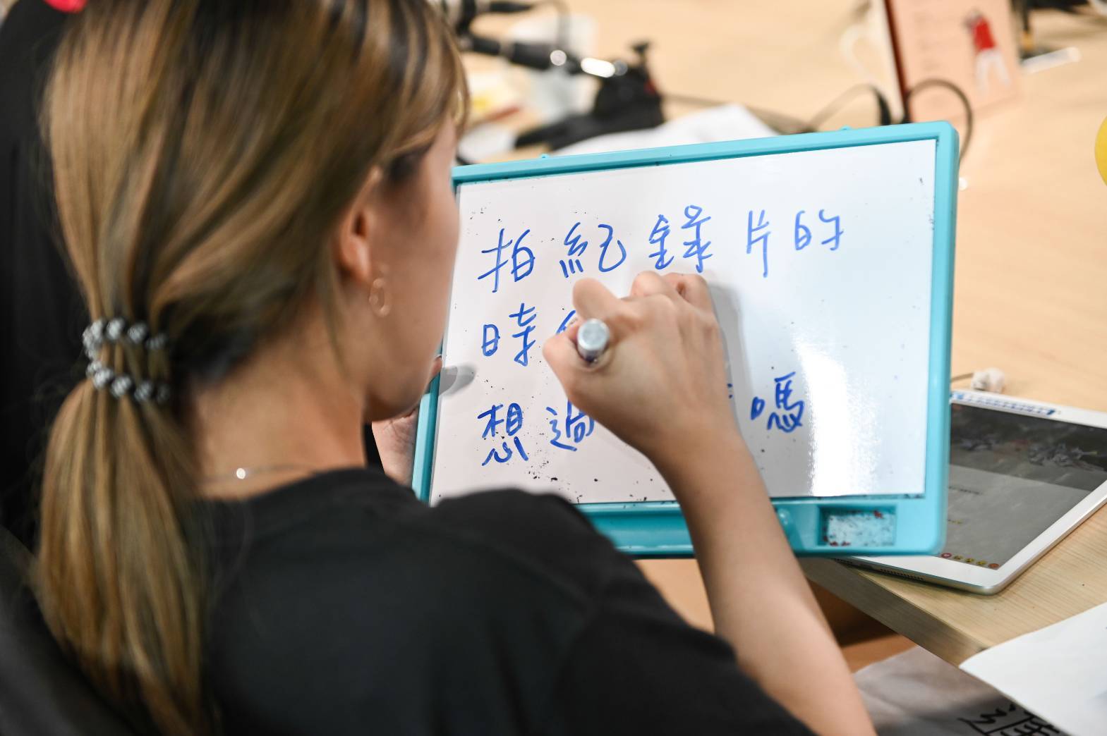 嶺東科技大學負責直播的學生，細心地將粉絲問題寫在白板上提醒主持人