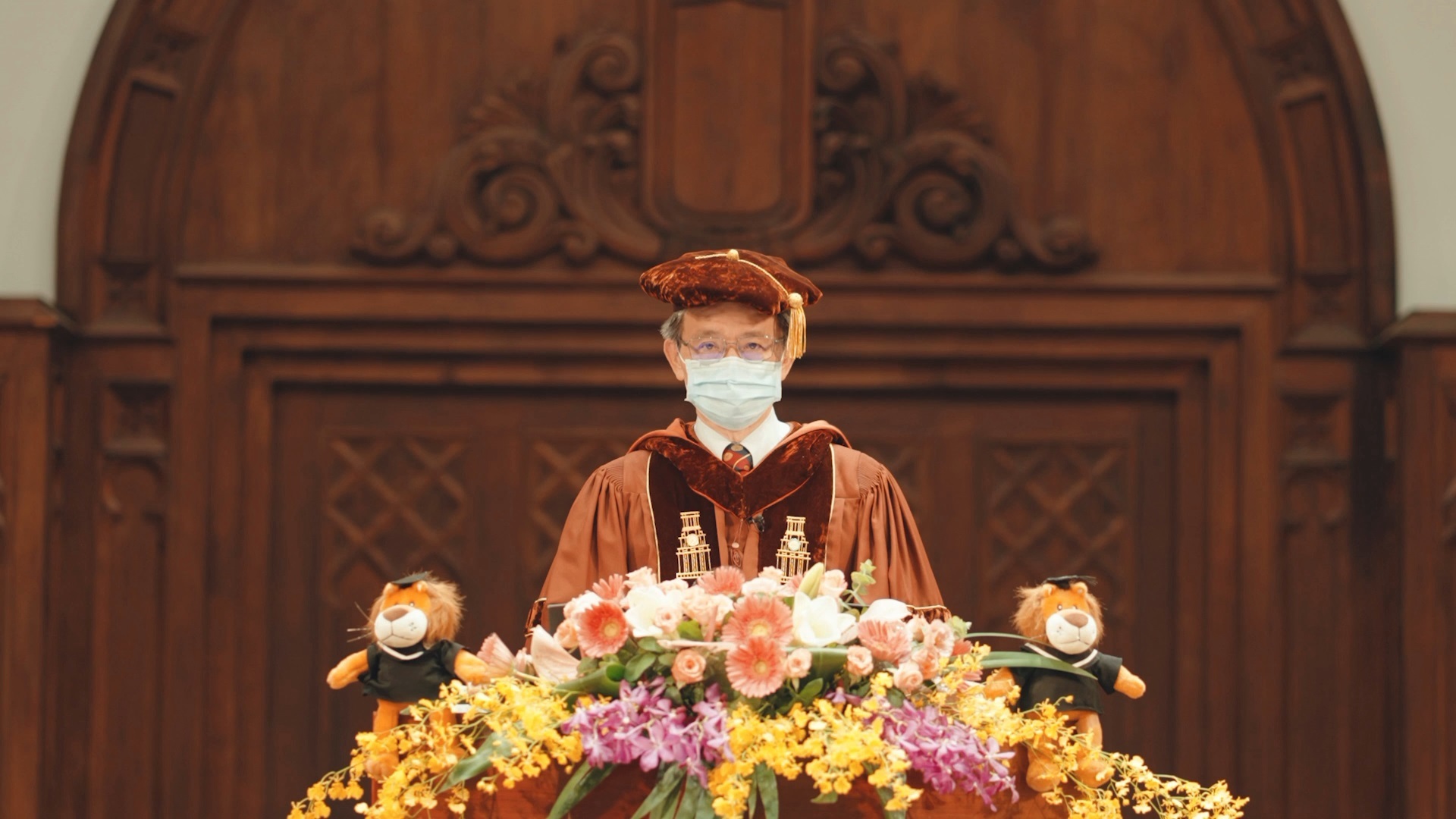 因疫情改為線上畢業典禮，吳正己校長身著博士袍在講臺致詞