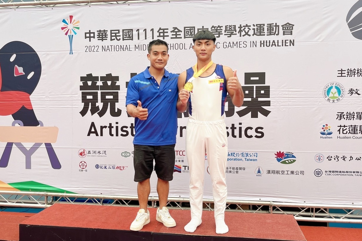 臺東高中黃彥章(右)於全中運競技體操個人全能競賽奪金，與教練游朝偉(左)合影。