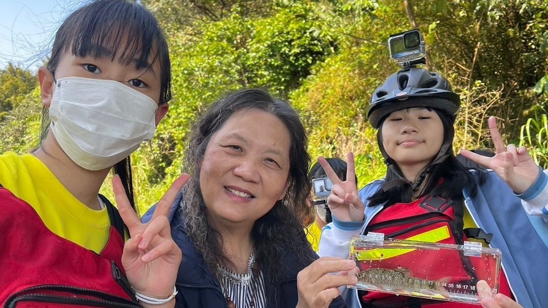 探訪貢寮在地的溪流，孩子將溪流中找到的生物，放在透明盒子裡觀察。(中為貢寮實中校長劉松英)