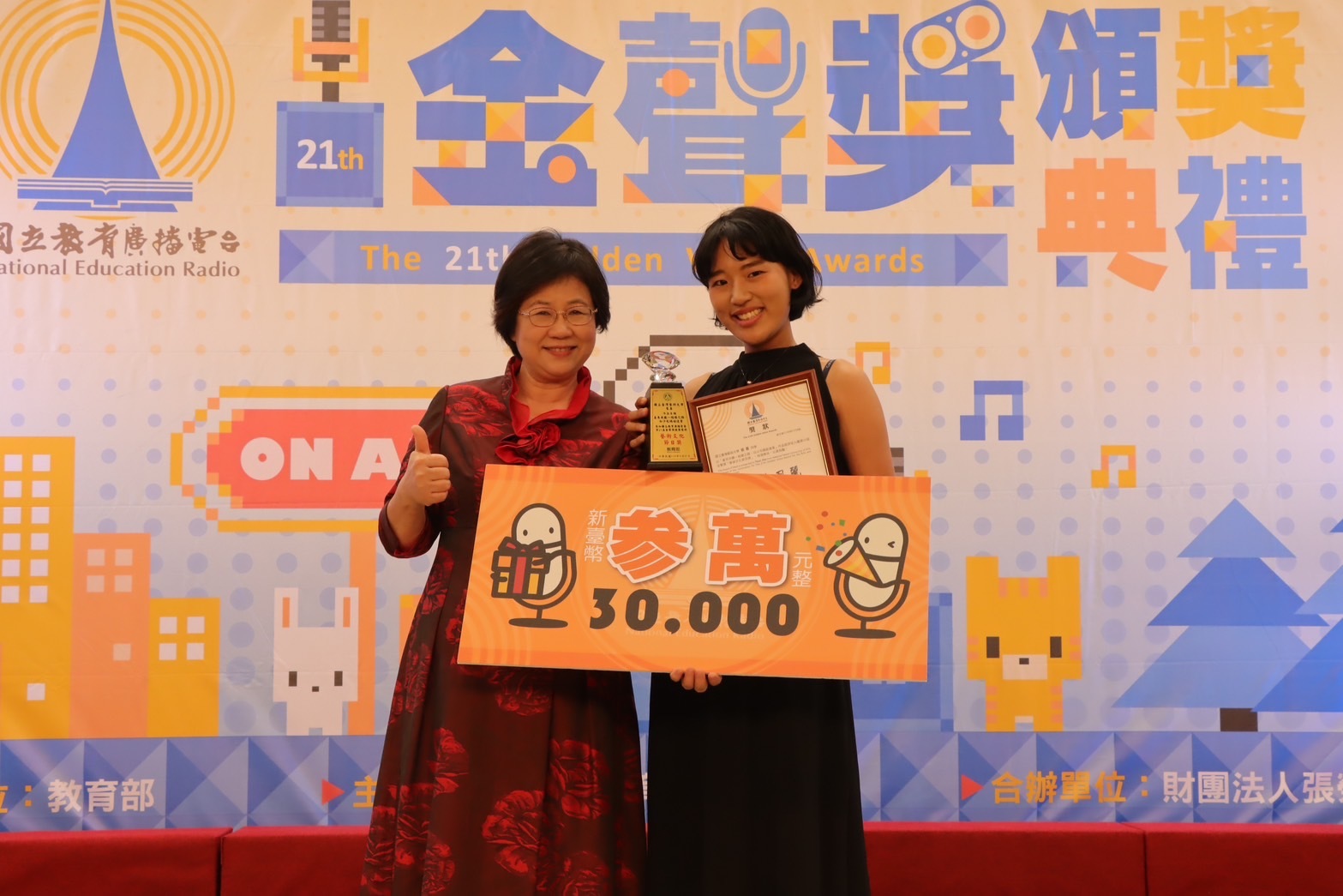 教育電臺黃月麗臺長(左)頒發獎項給獲獎同學