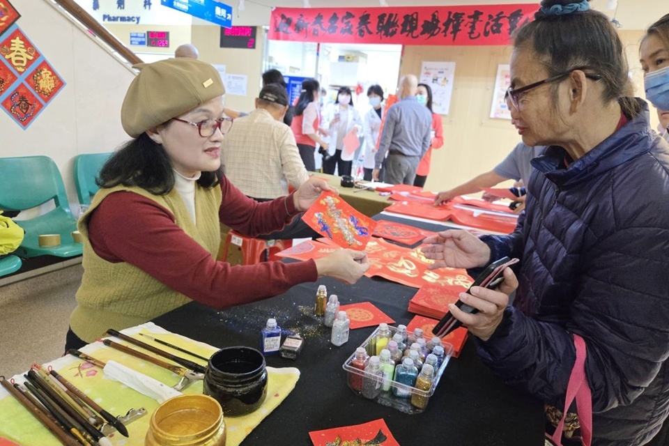 書法家鄭聘嬴(左)於臺東馬偕醫院辦理快閃揮毫贈春聯，為民眾及醫護人員客製創意春聯。