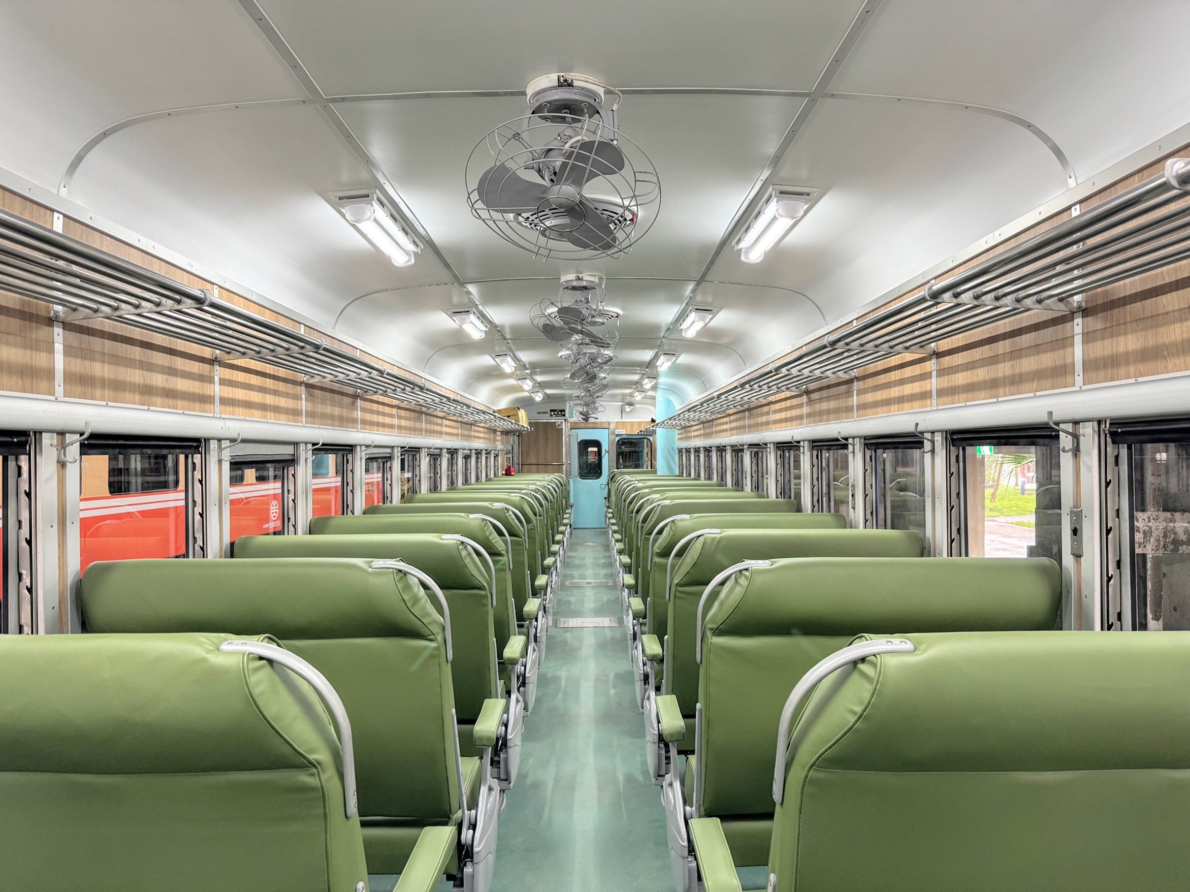 修復完成的藍皮柴油客車內裝以可翻轉方向的草綠色座椅搭配灰色旋轉吊扇，再現經典。(文化部提供)