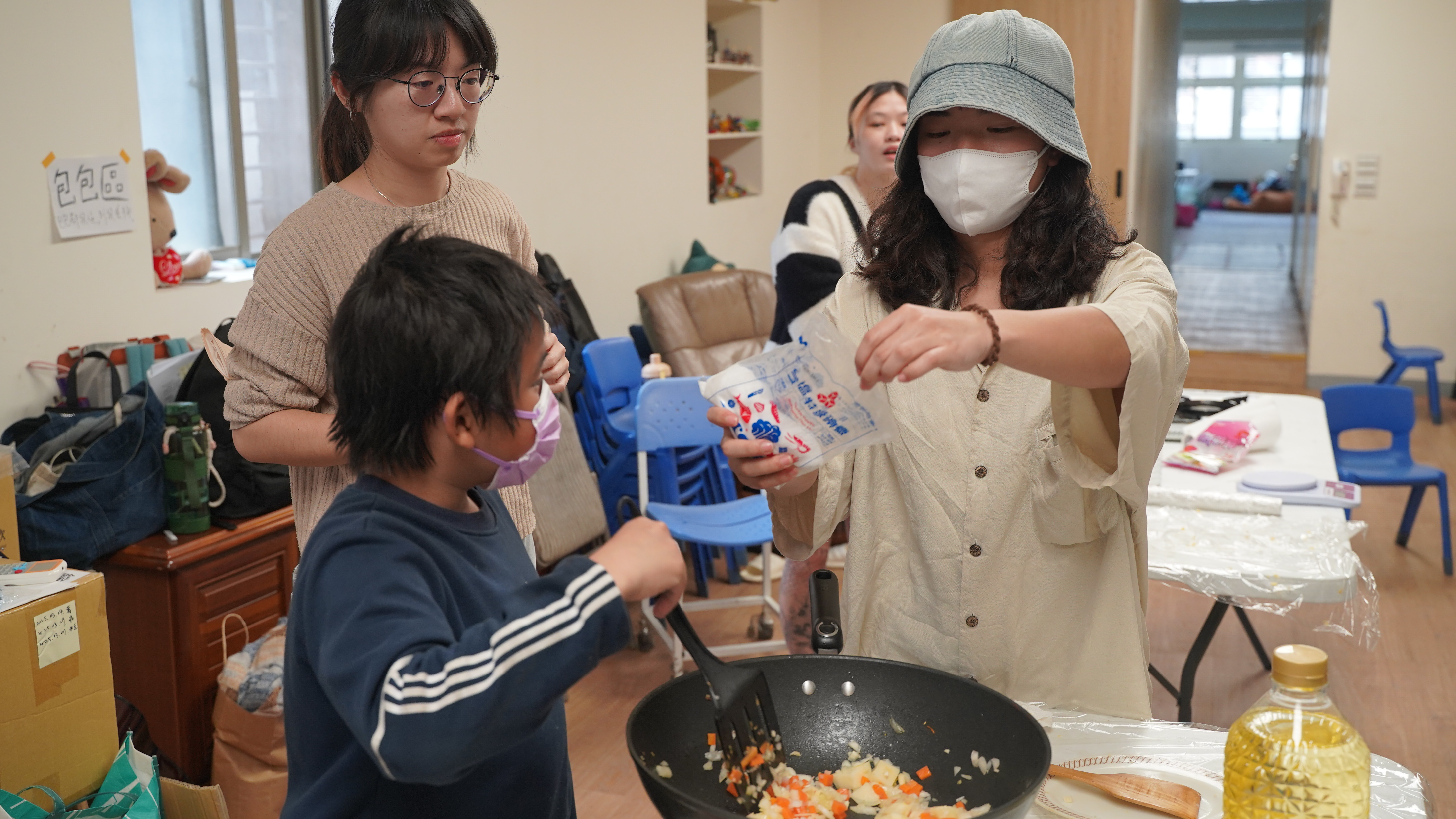 就業培力志工陪著孩子在餐車課中學習烹煮食物（照片提供：微光盒子）