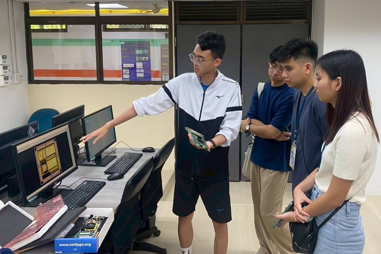 中原大學電機系研究生向菲律賓學生介紹「積體電路設計共構實驗室」中的AI運算設備與應用。(中原大學提供)