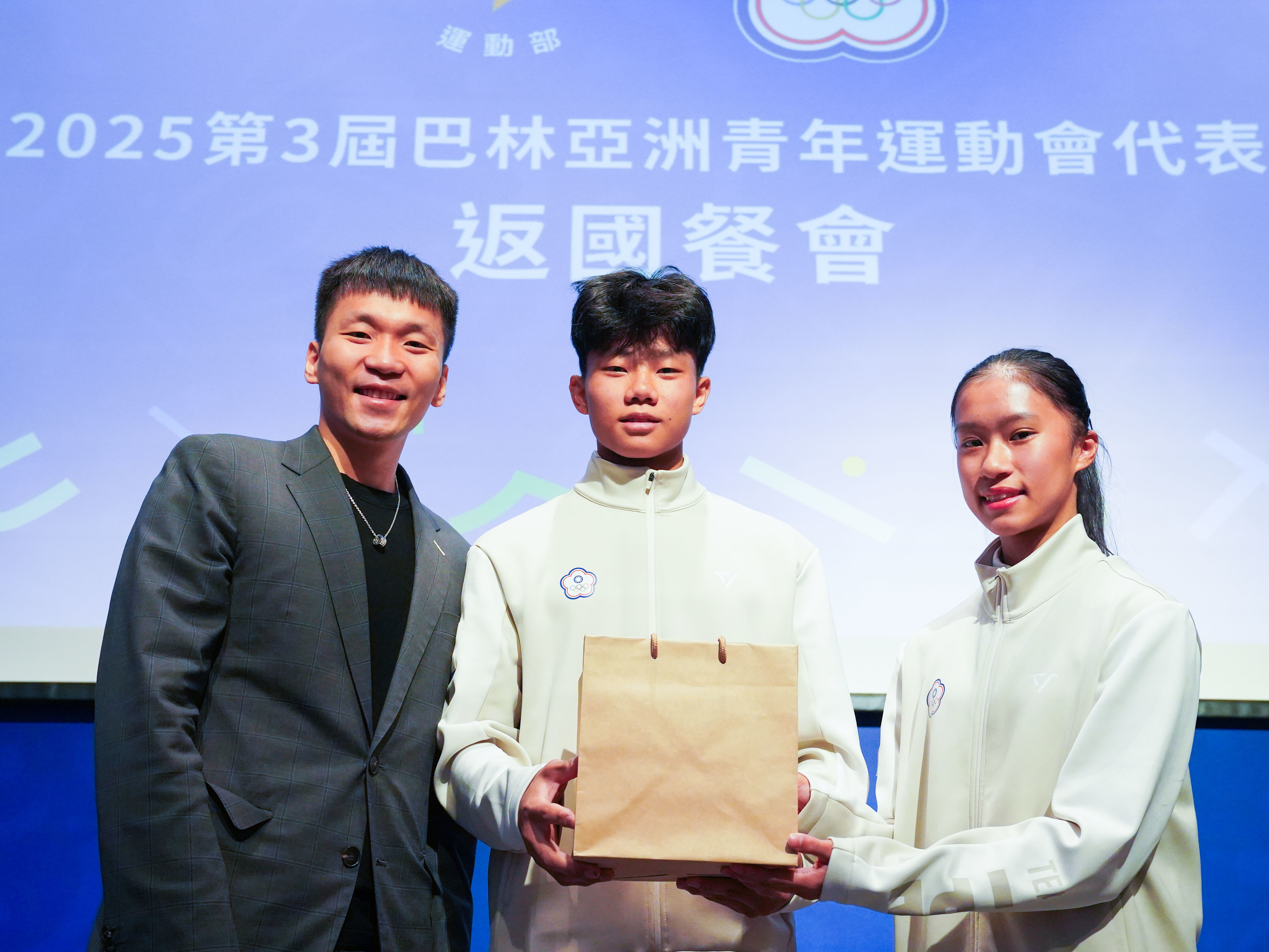 李洋部長致贈禮品，由黃迺軒（中）、潘筱晴（右）選手代表接領。(運動部提供)